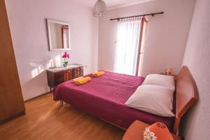 a bedroom with a bed with a purple blanket and a window at Kristian Apartments in Rovinj
