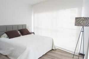 a bedroom with a white bed and a lamp at ESPECTACULAR LOFT in Quito