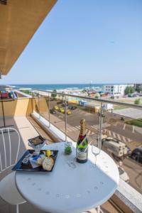 a table with a bottle of wine and glasses on a balcony at Summerland Happy Blue Apartments in Mamaia
