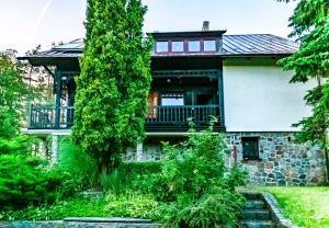 a stone house with a balcony and trees at Leśniczówka WIEŻYCA in Szymbark