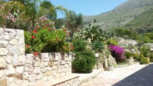 a garden with flowers and a stone wall at Case Susinna in Capaci