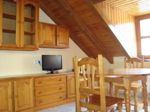 une salle à manger avec une table et une télévision dans l'établissement Apartamentos Saila, à Castejón de Sos