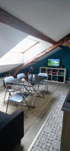 ein Wohnzimmer mit einem Tisch und Stühlen sowie einem TV in der Unterkunft Casabann in Langrune-sur-Mer