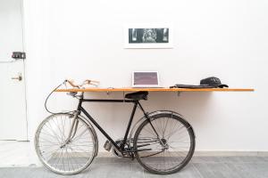 una bicicleta estacionada junto a un escritorio con un ordenador portátil en N'Art Suites - Napoli, en Nápoles