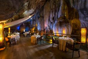 een restaurant in een grot met tafels en stoelen bij The Banjaran Hotsprings Retreat in Ipoh