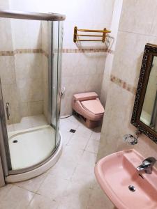 uma casa de banho com um chuveiro e um WC cor-de-rosa. em My Vigan Home Hotel em Vigan