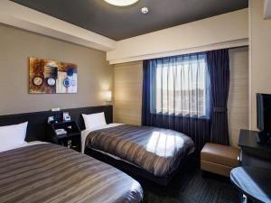um quarto de hotel com duas camas e uma televisão em Hotel Route-Inn Kashiwa Minami -KOKUDO 16GOU ZOI- em Kashiwa