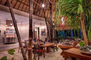 a restaurant with wooden tables and palm trees at Emerald Maldives Resort & Spa-Deluxe All Inclusive in Raa Atoll