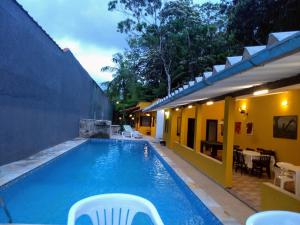 a swimming pool with chairs next to a house at Guaraú Praia Suítes in Peruíbe