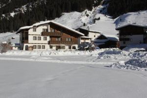 pokryty śniegiem budynek przed górą w obiekcie Haus Astoria w mieście St. Leonhard im Pitztal