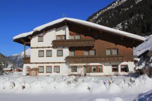 duży drewniany budynek z śniegiem na ziemi w obiekcie Haus Astoria w mieście St. Leonhard im Pitztal