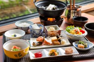 una mesa con platos de comida y tazones de comida en La Vista Akangawa, en Akankohan