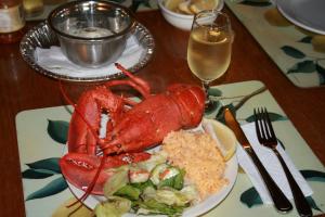 a lobster on a plate with a salad and a glass of wine at Tuckamore Lodge in Main Brook