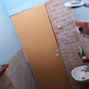 un bagno con porta marrone accanto a un lavandino di Salty Dog Hostel a Telukdalem Altre 30 foto