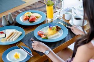 a woman sitting at a table with plates of food at Villa Cendrawasih Ubud in Tegalalang