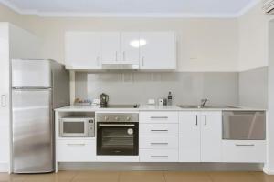 a kitchen with white cabinets and white appliances at Quest on Story Bridge in Brisbane