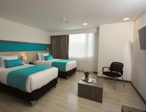 a hotel room with two beds and a chair at Hotel Nivari Duitama in Duitama