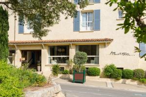 um edifício com persianas azuis numa rua em Best Western Hotel Matisse em Sainte-Maxime