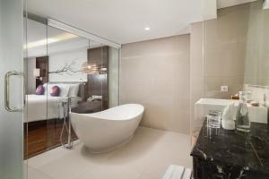 un bagno con vasca bianca e una camera da letto di FOX Hotel Jimbaran Beach Bali a Jimbaran