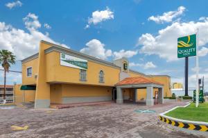 un bâtiment jaune avec un panneau devant lui dans l'établissement Quality Inn Piedras Negras, à Piedras Negras