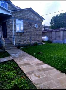 a house with a stone walkway in front of a yard at Sweet home Gusar. in Qusar