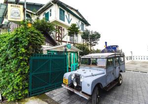 stary samochód zaparkowany przed domem w obiekcie Cochrane Place Hotel w mieście Kurseong