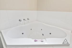 a white bath tub with two faucets in a bathroom at Jurien Bay Tourist Park in Jurien Bay