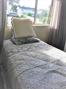 a bed with a pillow in front of a window at Sylvia Park House in Auckland