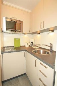 a white kitchen with a sink and a microwave at Belvedere 68 in Großenbrode