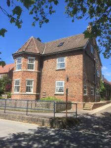 a brick building with a fence in front of it at Harmony House Boutique B&B in Stillingfleet