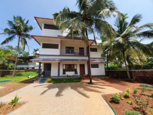 a house with palm trees in front of it at Monsoon Apartments in Kannur