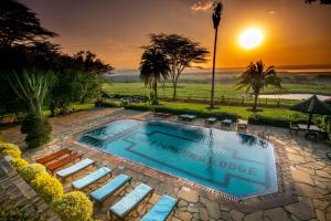 a swimming pool with lounge chairs and a sunset at Lake Nakuru Lodge in Nakuru