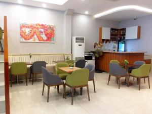 ein Esszimmer mit Tischen und Stühlen sowie eine Küche in der Unterkunft Hue My Hotel in Ho-Chi-Minh-Stadt