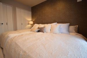 a large bed with white pillows in a bedroom at TOCORO. Mt. Fuji Yayoi in Fujikawaguchiko