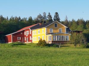 une grande maison jaune et rouge dans un champ dans l'établissement Nygården B&B Hälsingegård, à Harmånger