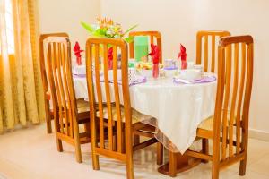 mesa de comedor y sillas con mantel blanco en Charis Home Services en Accra