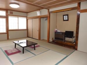 Togakushi- Kogen Minshuku Rindo في ناغانو: غرفة معيشة مع طاولة وتلفزيون