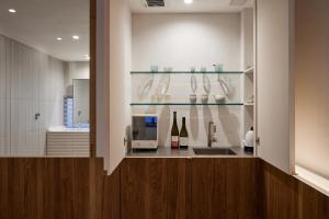 滔々 御崎 二階の宿 toutou Onzaki Nikai no Yado في كوراشيكي: مطبخ مع كونتر مع زجاجات النبيذ ومغسلة