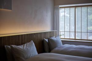a bedroom with two beds and a window at 滔々 御崎 二階の宿 toutou Onzaki Nikai no Yado in Kurashiki