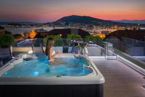 a woman sitting in a bath tub on a balcony at Villa Muller Apartments in Split