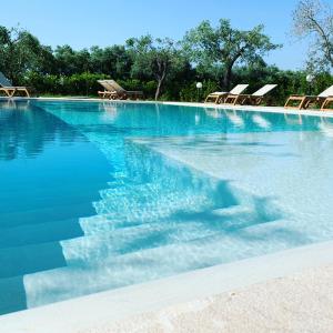 a swimming pool with chairs and blue water at Agriturismo Terra Rossa in Otranto