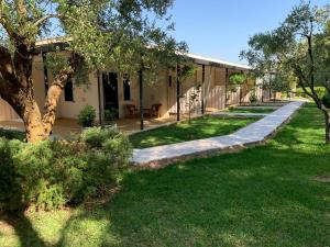 une passerelle menant à un bâtiment avec des arbres et de l'herbe dans l'établissement Agriturismo Terra Rossa, à Otrante