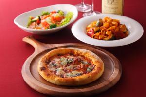a table with a pizza and a plate of food at Hotel Y's (Adult Only) in Sapporo