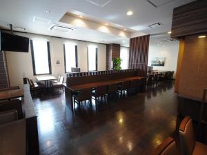 薩摩川内市にあるホテルルートイン薩摩川内の広い客室で、レストラン内のテーブルと椅子が備わります。