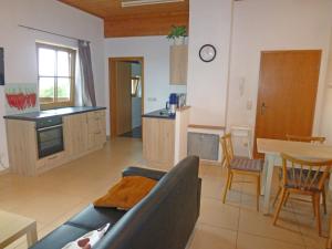 ein Wohnzimmer und eine Küche mit einem Sofa und einem Tisch in der Unterkunft Ferienwohnung Bösch in Taching am See