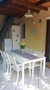 a white table with white chairs and a vase of flowers at Petite maison proche océan Boulevard de l'amelie in Soulac-sur-Mer
