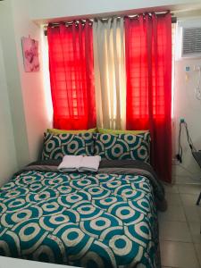 Schlafzimmer mit roten Vorhängen und einem Bett mit Tagesdecke in der Unterkunft Shanilyn Residency Urban Deca Towers EDSA mandaluyong Unlimited INTERNET AND NETFLIX in Manila