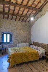 a bedroom with a large bed in a stone wall at Can Gich Espacio Rural in Celrá