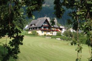 ein großes Haus auf einem grünen Feld in der Unterkunft Sommereck Appartements in Seeboden