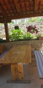 a wooden picnic table with a bench under a roof at Apartments Juric in Mimice